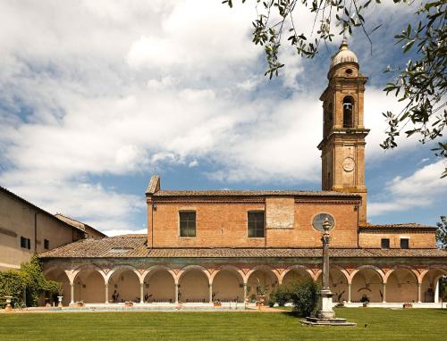 un grande edificio in mattoni con torre dell'orologio di Hotel Certosa Di Maggiano a Siena