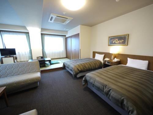 um quarto de hotel com duas camas e um sofá em Route Inn Grantia Hidatakayama Wakura no yado em Takayama