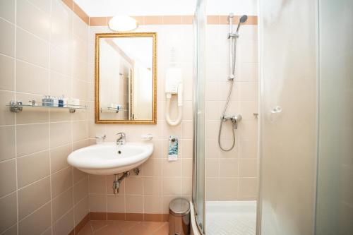 a bathroom with a sink and a shower with a mirror at Amadria Park Hotel Agava in Opatija