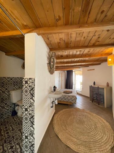 Habitación con techos de madera y alfombra grande. en Surf HouseMaroc en Esauira