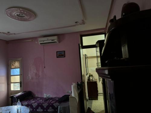 a living room with a pink wall and a tv at appart charaf in Taza