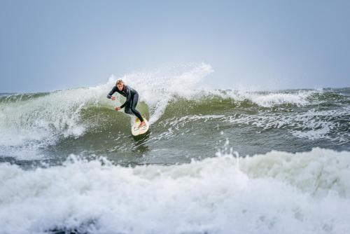 un homme faisant une vague sur une planche de surf dans l'océan dans l'établissement Visit Örestrand, à Strandbaden