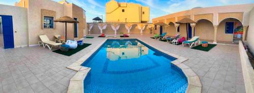 einen Pool in einem Innenhof mit Stühlen und einem Gebäude in der Unterkunft Dar Melody in Djerba