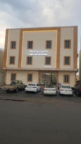 a large building with cars parked in a parking lot at درة الشرق للشقق المخدومة in Medina