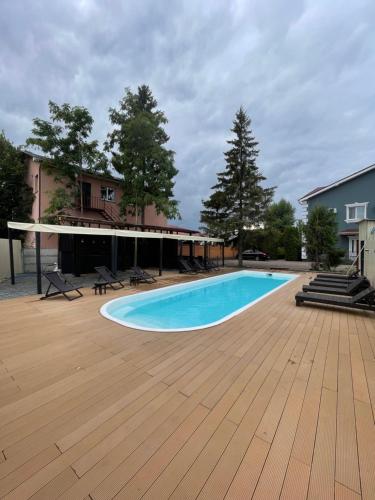 una piscina con terraza de madera y una casa en Old School Villa en Gnedin