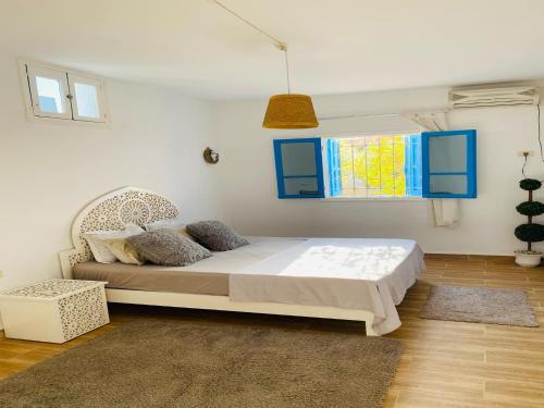 a bedroom with a bed with blue cabinets and a window at Le Refuge Djerbien in Houmt Souk