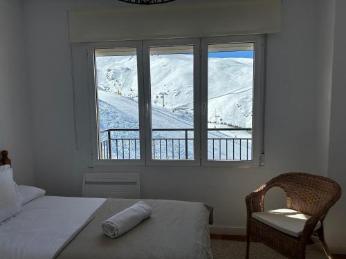 een slaapkamer met een bed, een stoel en een raam bij Luxury Apartment Zona baja in Sierra Nevada