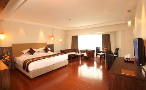 Habitación de hotel con cama y sala de estar. en The Altruist Business Hotel Kharadi, en Pune