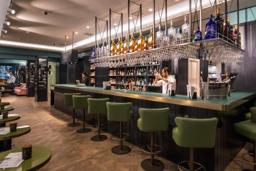 un bar dans un restaurant avec des tabourets de bar verts dans l'établissement Vincci The Mint, à Madrid