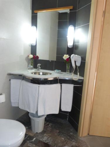 a bathroom with a sink and a toilet and towels at Hotel Arena Fes in Fez