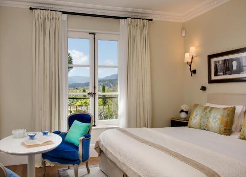 a bedroom with a bed and a table and a window at Domaine du Mas De Pierre in Saint Paul de Vence