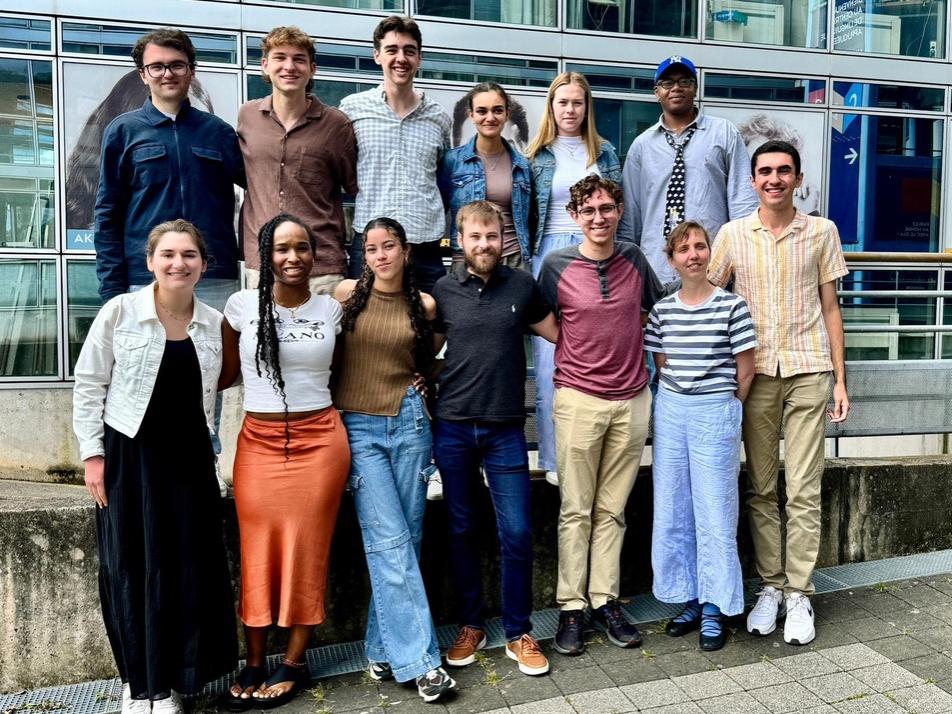 A group of 12 students and their professor lined up in two rows for a photo.