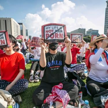 A group of women sit holding protest signs that read "My Life Is Not Your Porn"