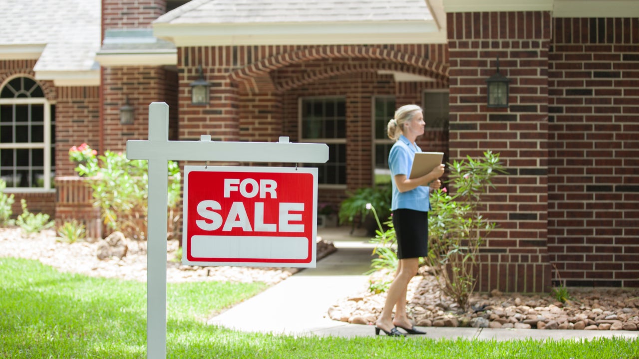 Real estate agent greets a client in front of a red brick home