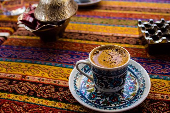 blue saucer with a cup of turkish coffee on a multicolored tablecloth