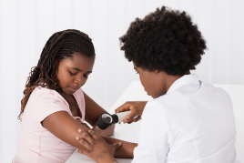 Dermatologist examining child’s skin to see if the bumps are molluscum contagiosum or another condition.