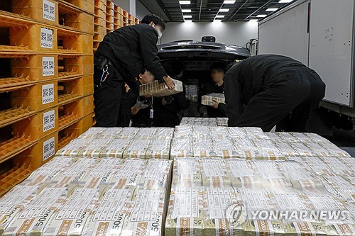 Security workers move bundles of cash at the Bank of Korea in Seoul on Feb. 5, 2024, as the central bank supplies funds to commercial banks. (Pool photo) (Yonhap)