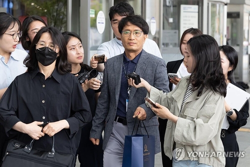 A police officer (front row, 2nd from R) is surrounded by reporters after stepping out from an interrogation session at a Seoul hospital on July 4, 2024, to question the driver involved in a deadly car crash that killed nine pedestrians in central Seoul earlier in the week. (Yonhap)