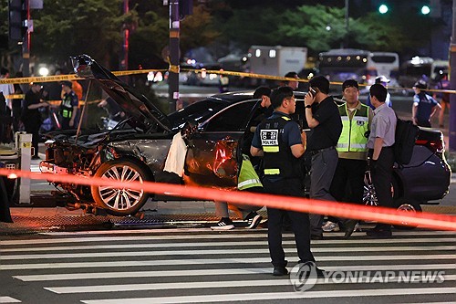 Police officers inspect a damaged vehicle after a deadly car crash near Seoul City Hall on July 1, 2024. (Yonhap)