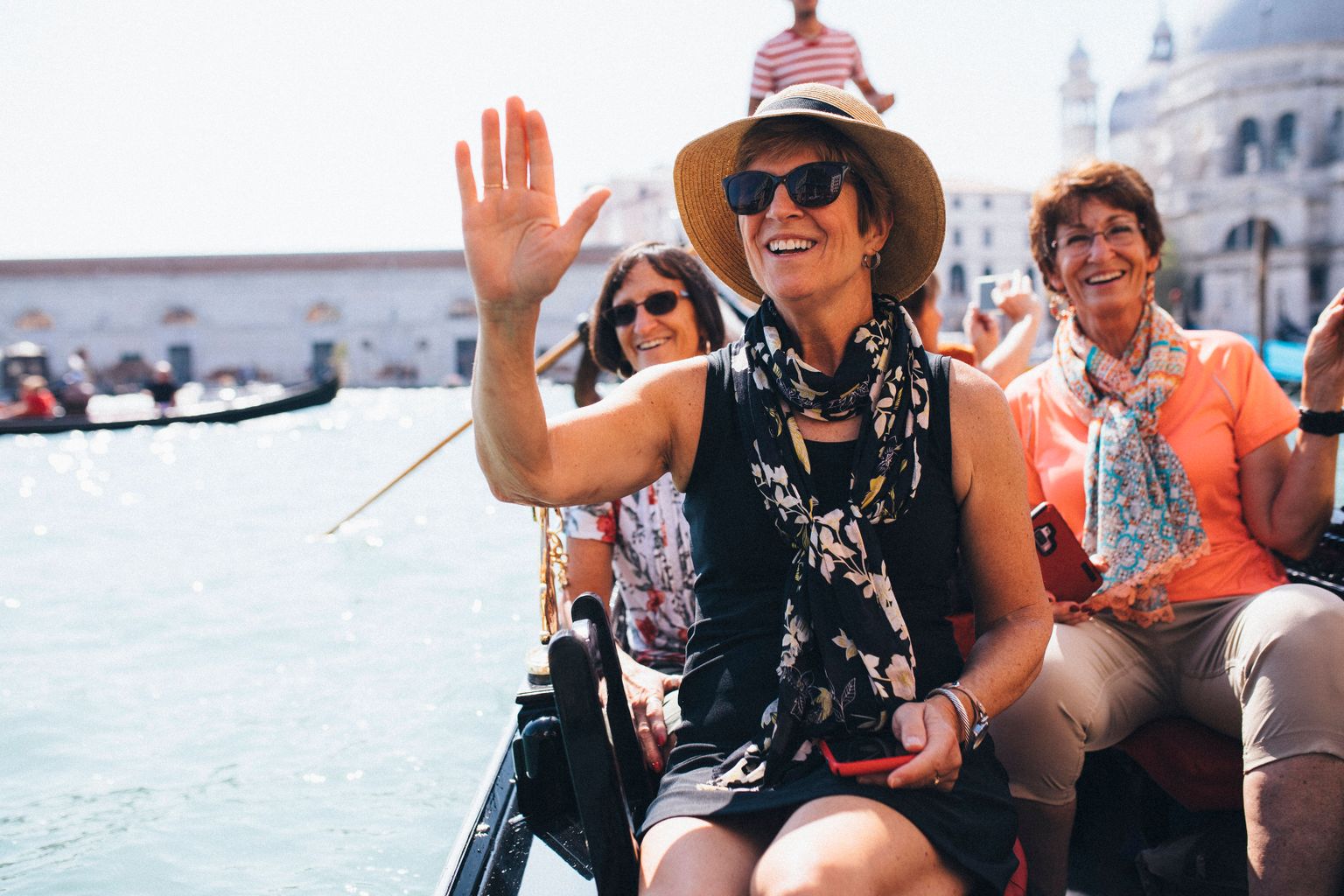 women riding a gondola, smiling and waving