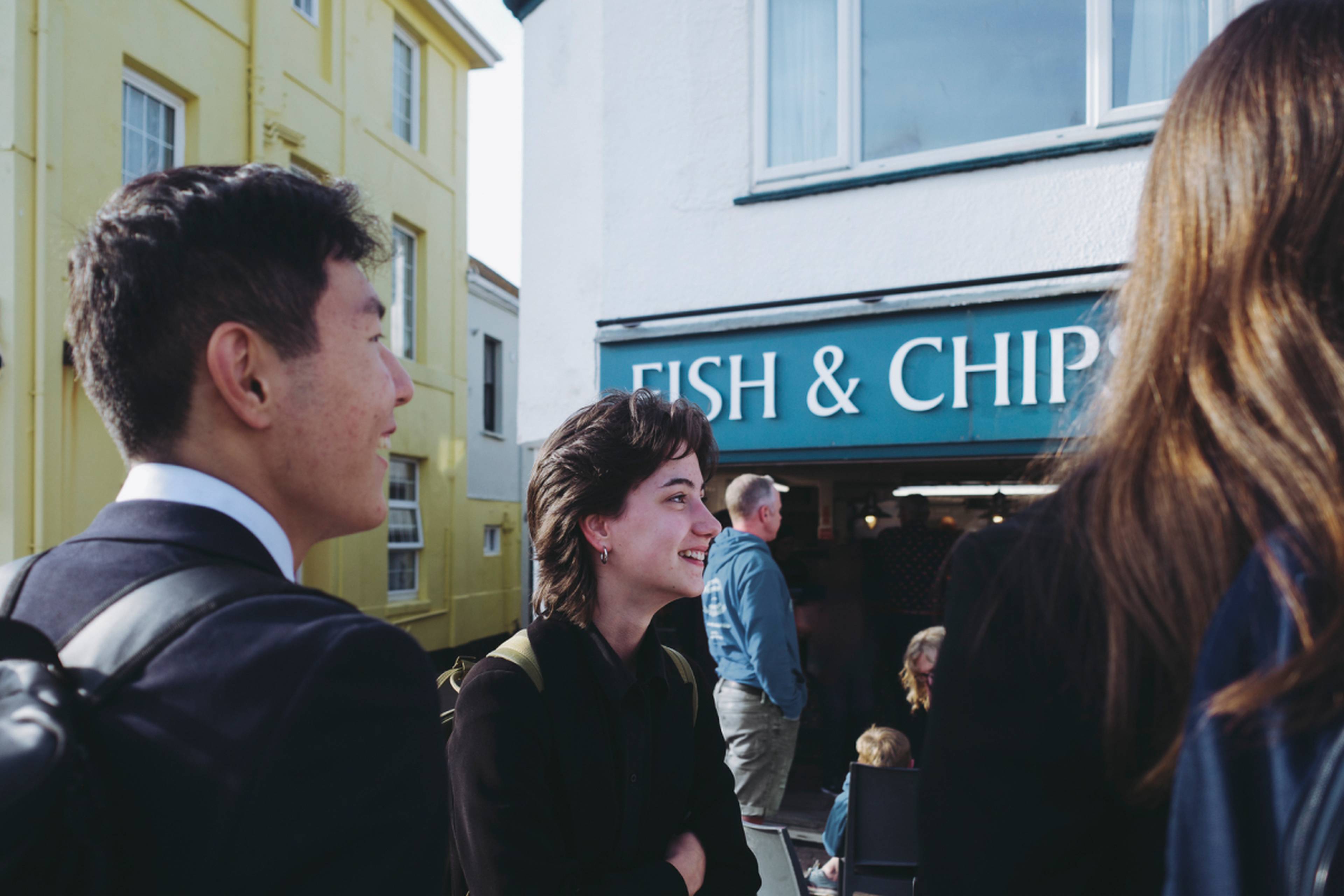 Friends standing in front of a fish and chips restaurant at the beach in UK