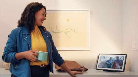 Una mujer tomando un café y disfrutando de un dispositivo Echo. 