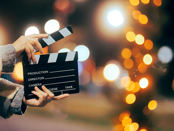 Hands holding a film slate on a street with sparkly lights in the background