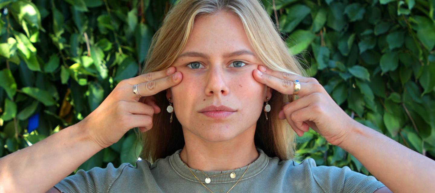 A model doing face yoga with fingertips on her cheekbones