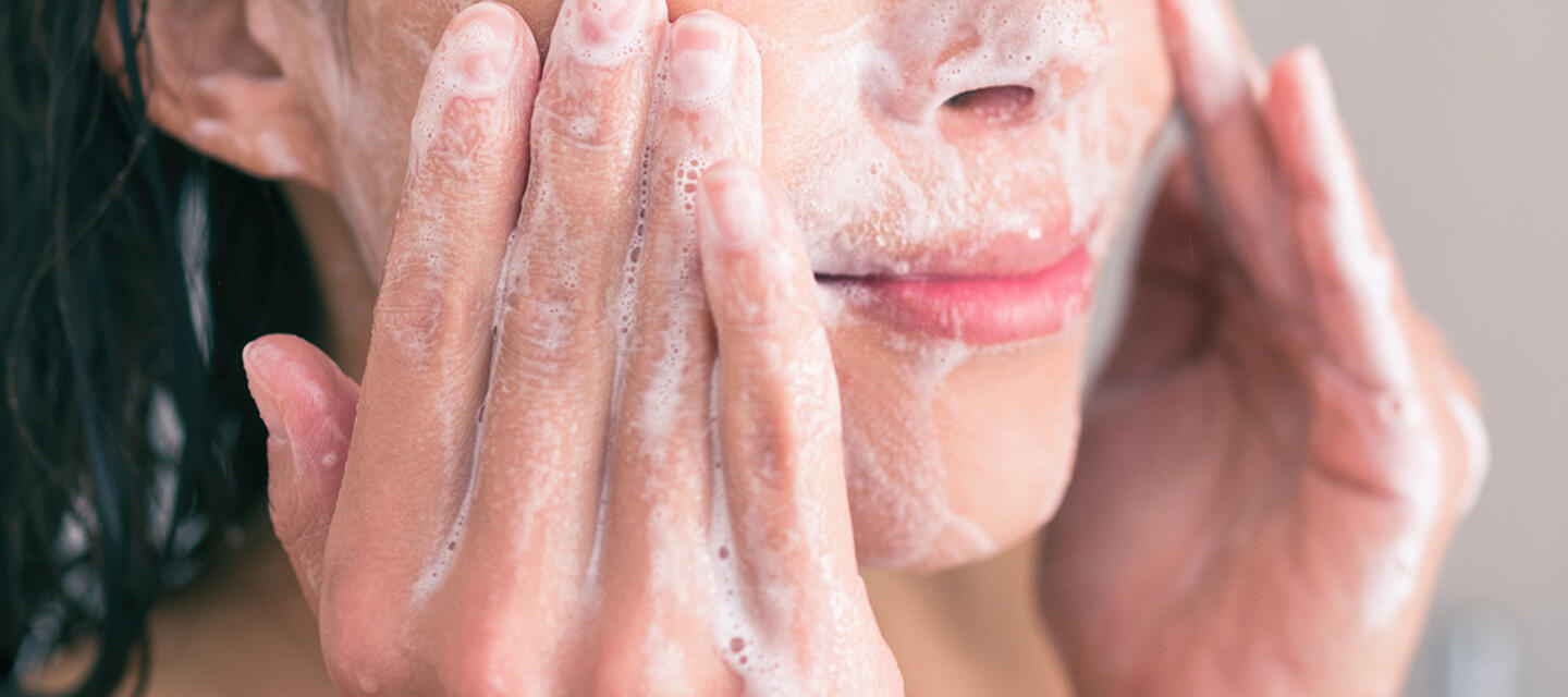 Closeup of a young woman washing her face with a cleanser