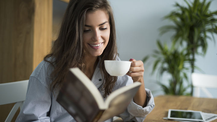 Woman reading a book and holding a cup of tea