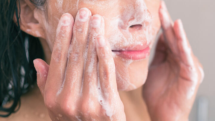 Closeup of a young woman washing her face with a cleanser