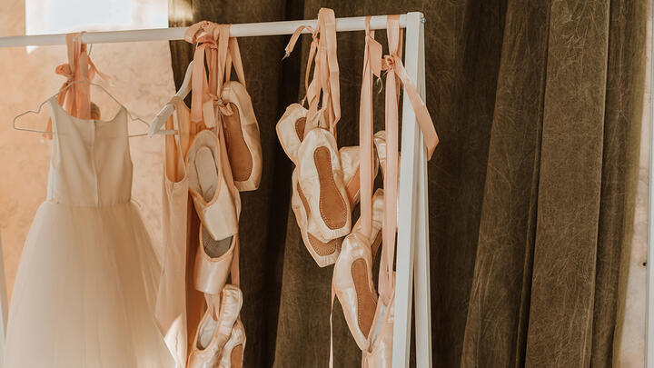 Pointe ballet shoes and dress hanging on a rank