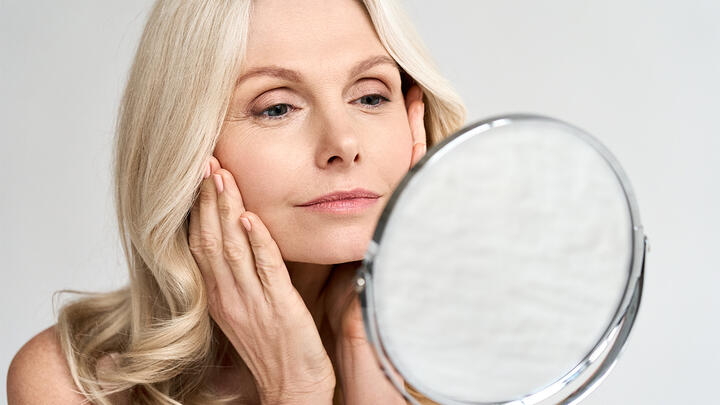 Middle-aged woman looking at her face in the mirror