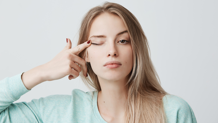 Young female model pressing her eyelid with her finger