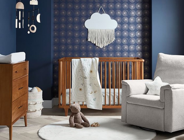 Cloud fringe mirror in nursery with white recliner, wooded crib and dresser.