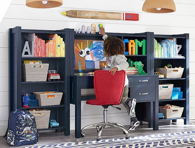 Young boy reaching for a toy on top of a desk