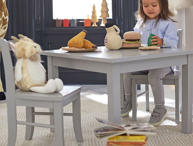 Kid sitting on My First Table chair with toy.