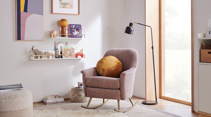 Blush rocking chair with gold legs in simple nursery 