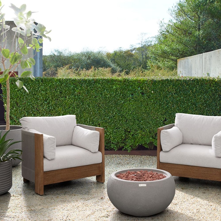 Round fire pit and outdoor chairs with cushions.