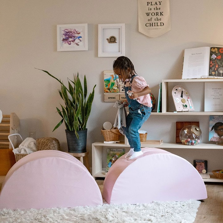 Child jumping between two pink foam tumblers