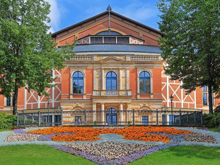 Das Festspielhaus Bayreuth mit buntem Blumenbeet davor.