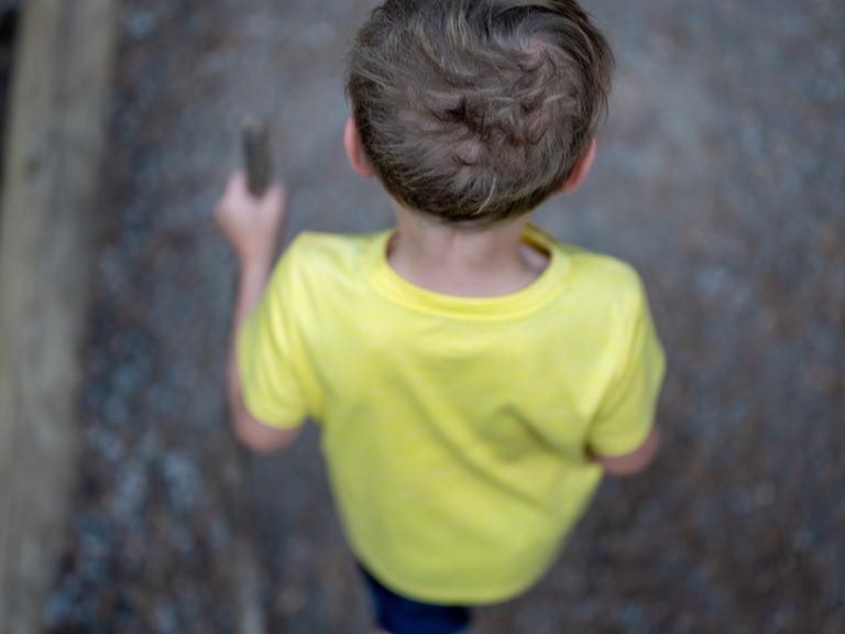 Man sieht einen Jungen von hinten und oben einen Weg entlang laufen.