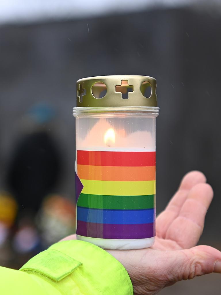 Eine Teilnehmerin einer Gedenkveranstaltung im Rahmen des Holocaust-Gedenktages, zum Gedenken an die Opfer des Nationalsozialismus, hält am Denkmal für die im Nationalsozialismus verfolgten Homosexuellen eine Grabkerze in Regenbogenfarben in der Hand.