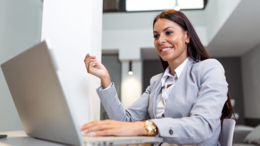 Young woman working from home, while in quarantine isolation during the Covid-19 health crisis. Portrait of a beautiful young business woman smiling and looking at laptop screen