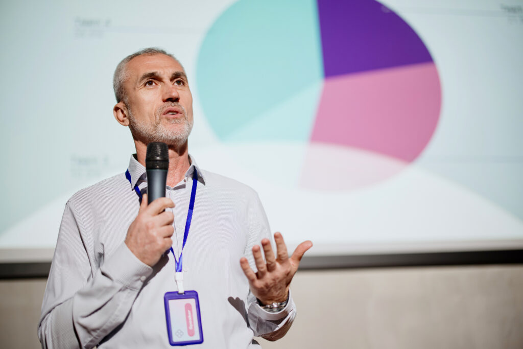 Public speaker giving a ted talk presentation at business event.