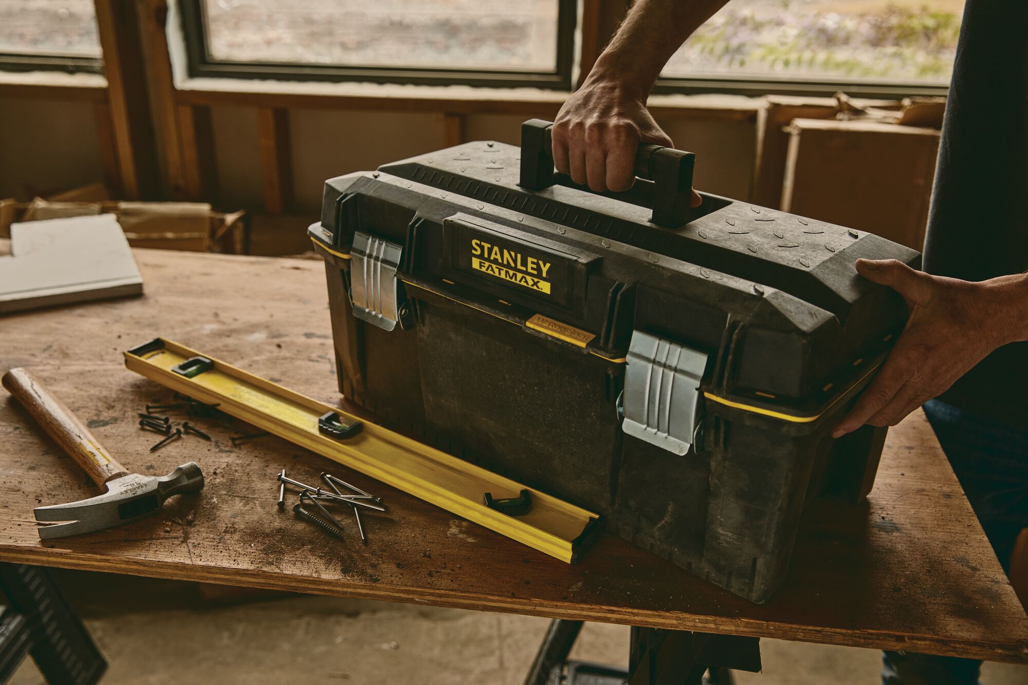 Person holding handle of 24 inch Series 2000 Tool Box with Tray placed on working table ready for use.