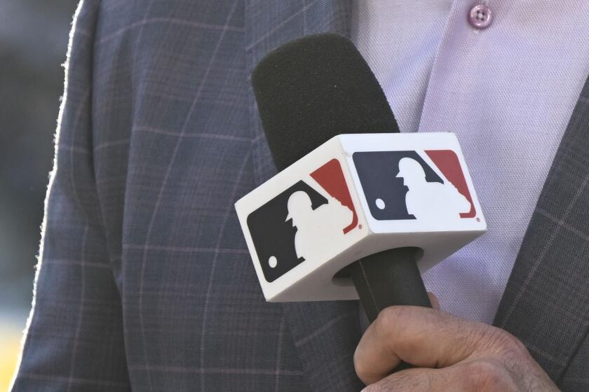 MLB broadcaster Mike Pomeranz holds a microphone before a baseball game between the Los Angeles Angels and the San Diego Padres on Monday, July 3, 2023, in San Diego. Major League Baseball's takeover of Padres' broadcasts involved months of planning, a playbook MLB is following this week with Arizona Diamondbacks' telecasts. (AP Photo/Denis Poroy)