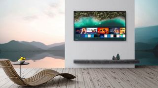 A Samsung Smart TV mounted on a wall in a room with wood flooring and a lounger.