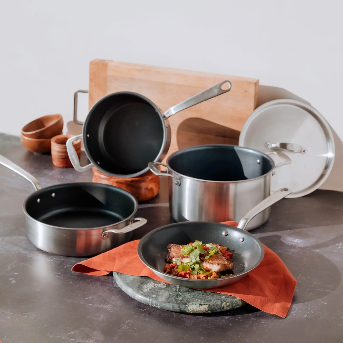 An assortment of cooking pots and pans on a kitchen counter with a dish of food presented in the foreground.