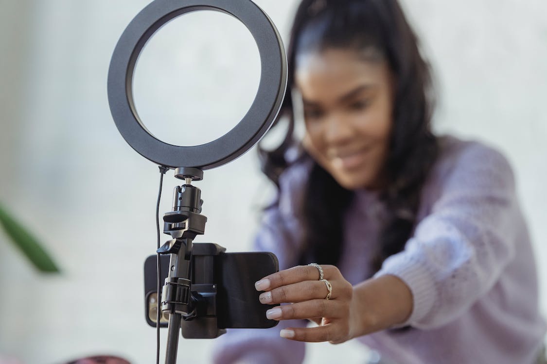 A TikTok influencer sets up their phone with a light ring in preparation to record a post.